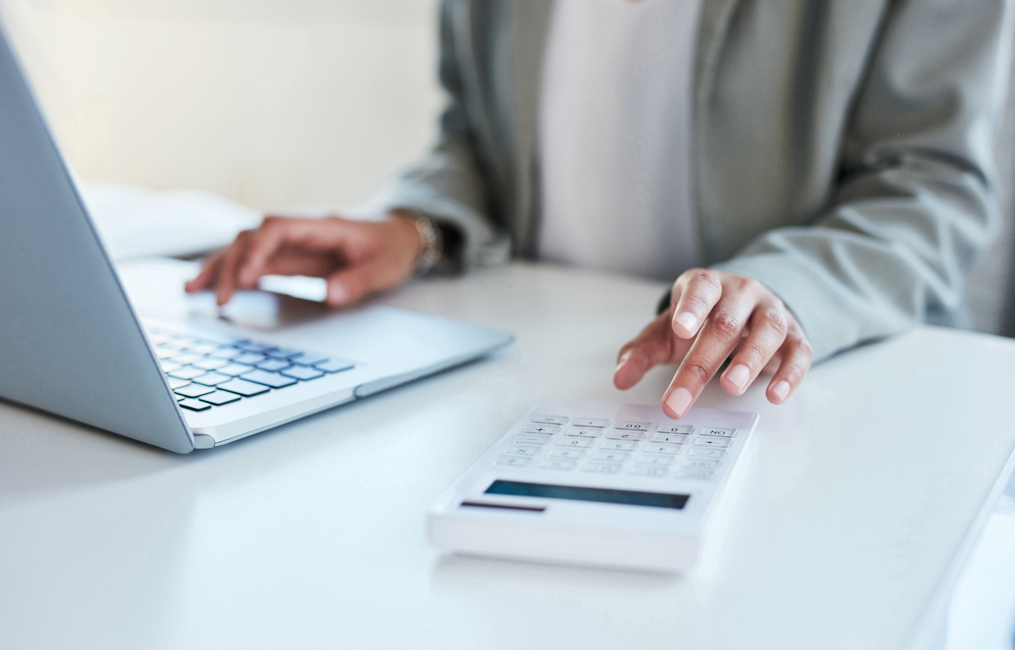 Closeup shot of an unrecognisable businesswoman using a calculator and laptop in an office